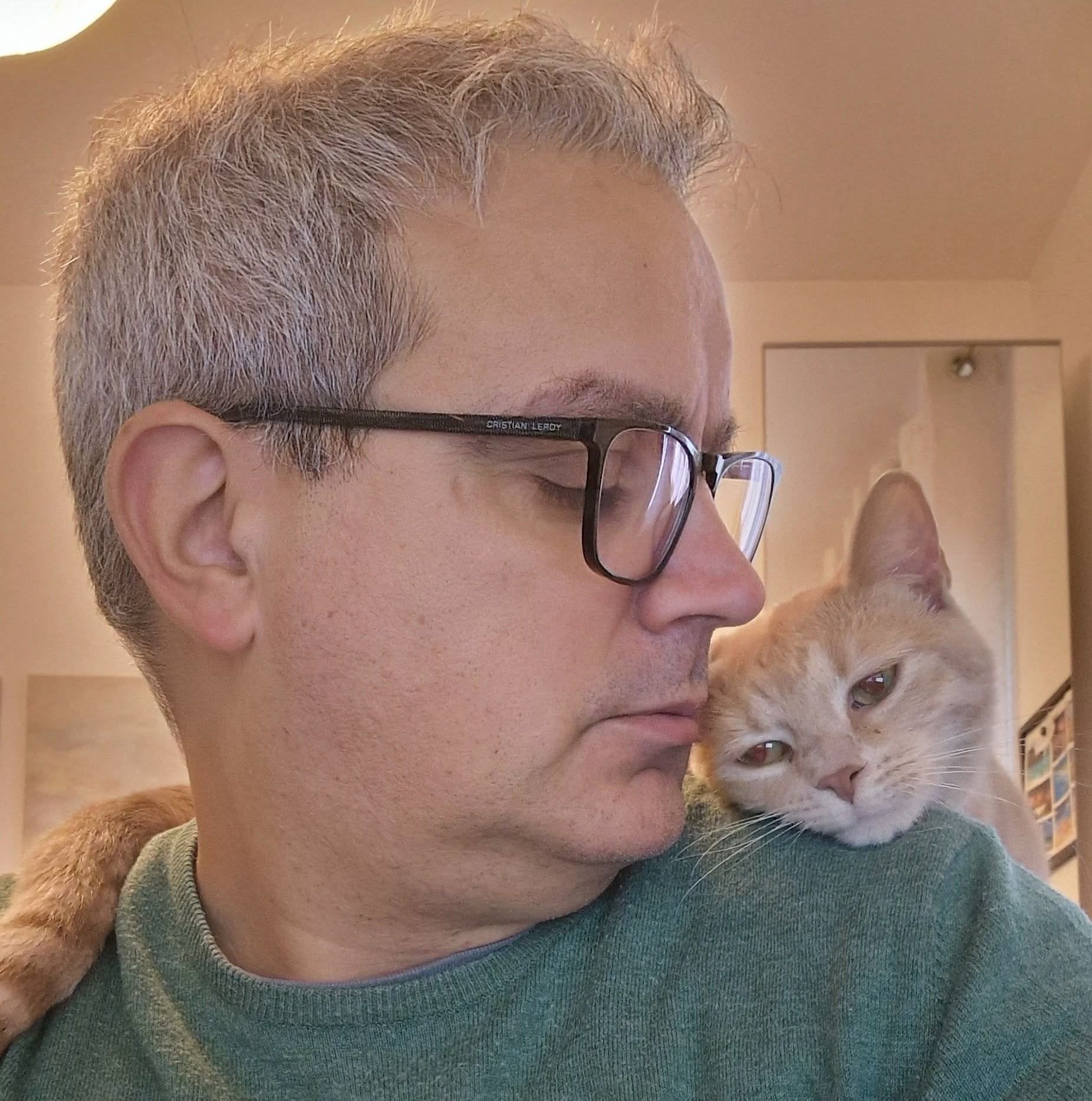 Renato, cat sitter professionale a Palermo, con un gatto arancione sulla spalla